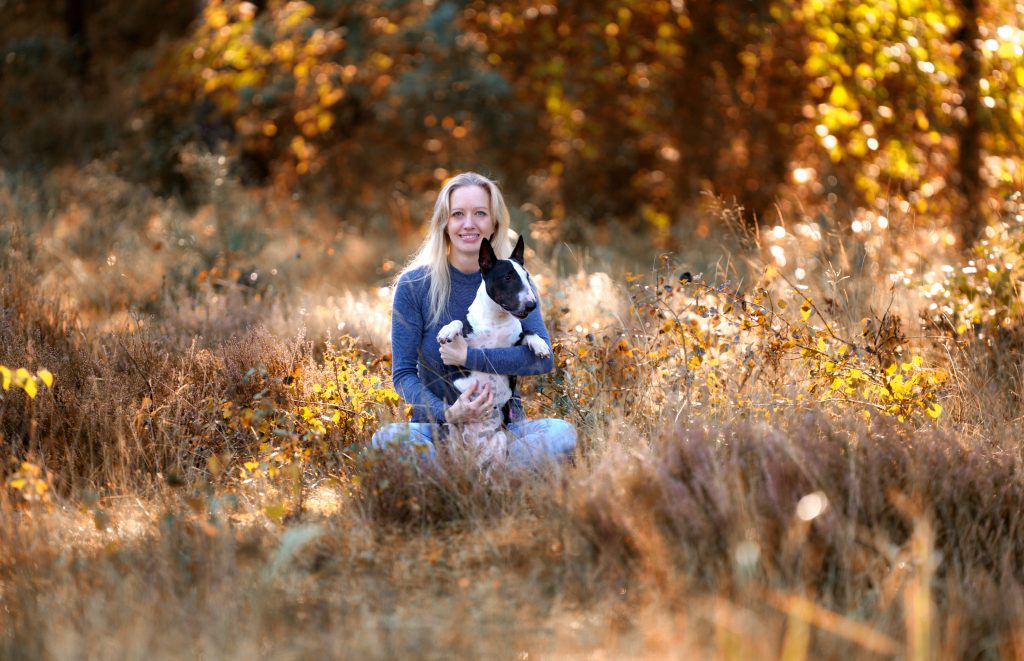 Sybille Thiele, psychologische Beraterin, sitzt mit Hund in einer Wiese.
